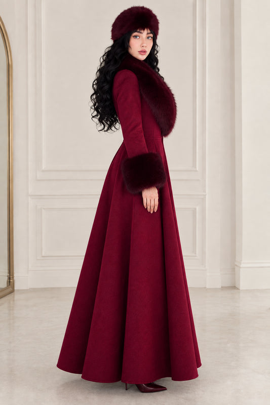 Side-angle view of woman in burgundy vintage-style full-length A-line coat