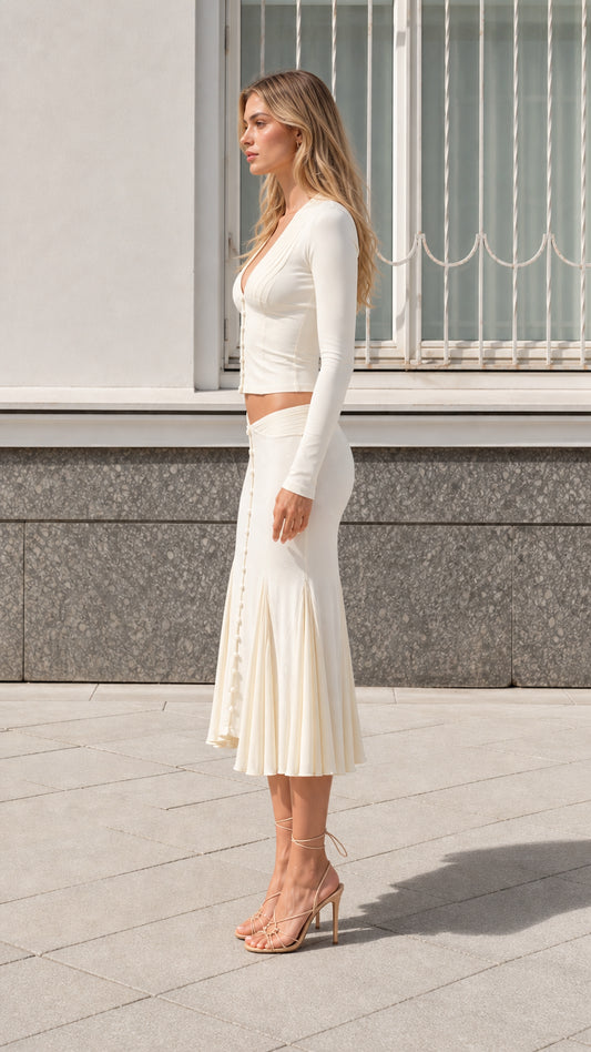 Side profile view of model wearing cream two-piece knit midi skirt set