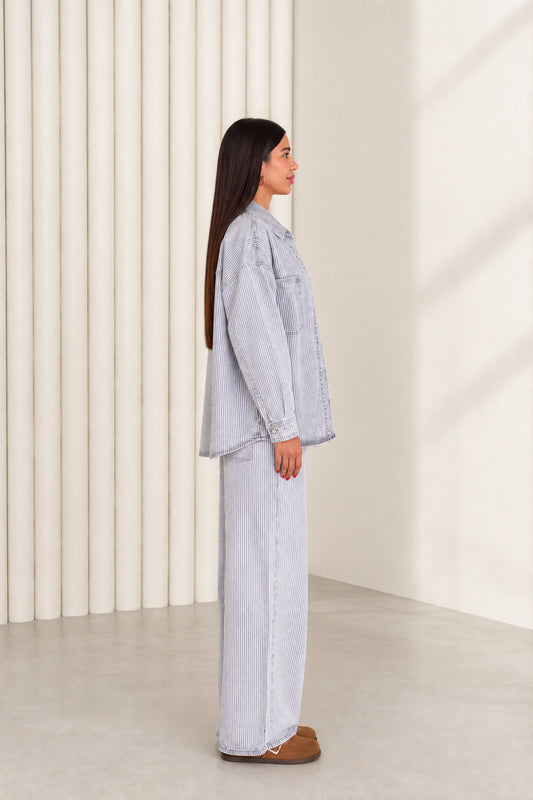 Side profile of model wearing light blue pinstripe denim matching two-piece set