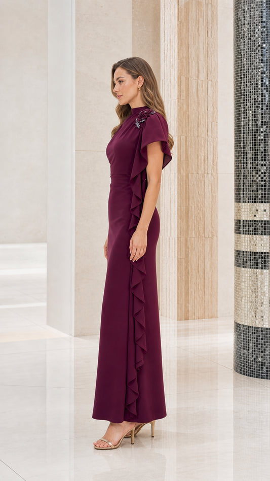 Side profile view of woman modeling the burgundy asymmetrical ruffle evening gown