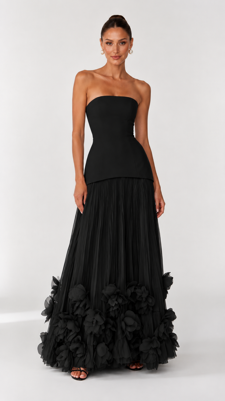 Front view of black strapless maxi dress with pleated skirt and dramatic floral hem