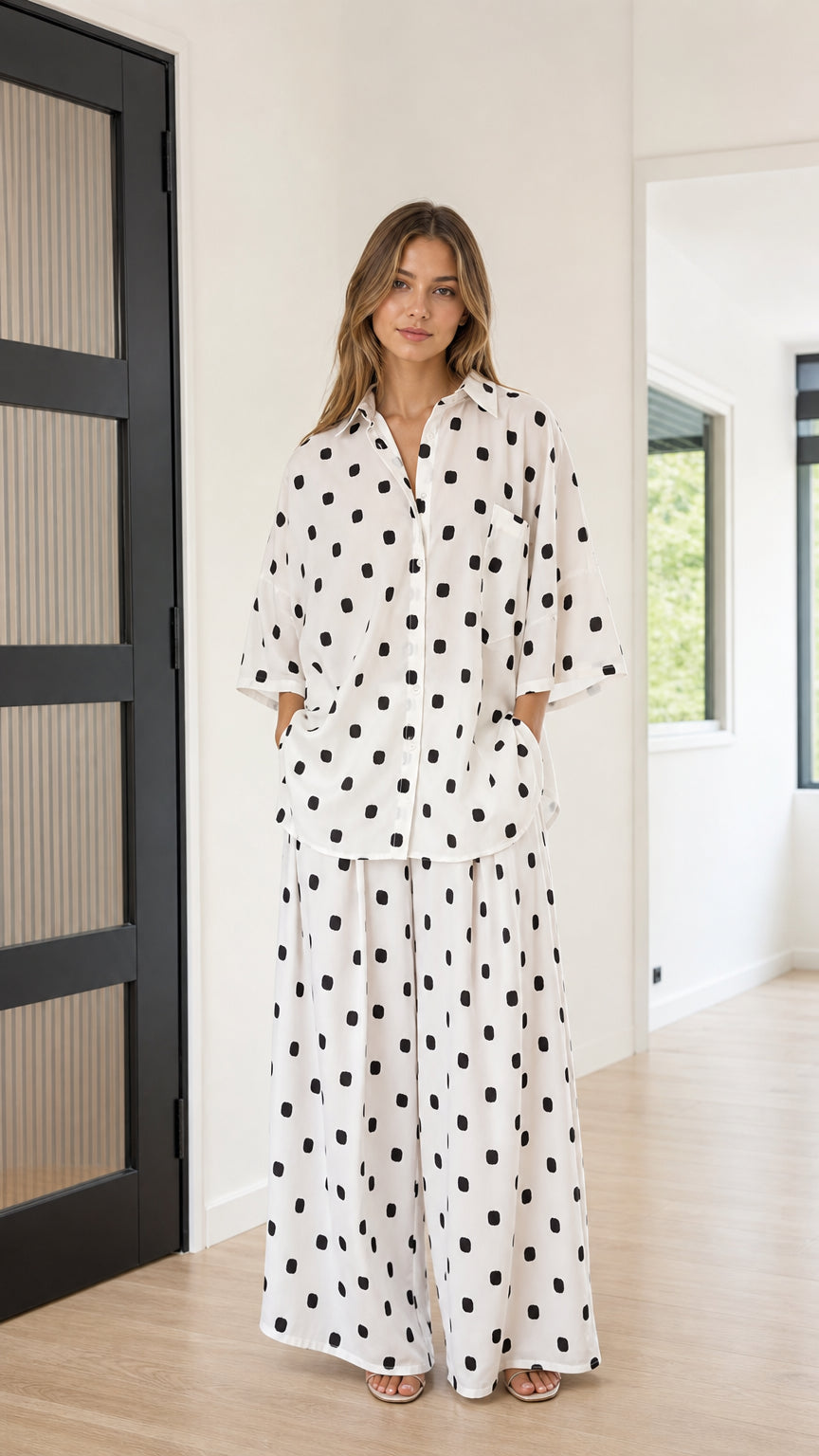 Full front view of model wearing white and black polka dot shirt and wide-leg pants set