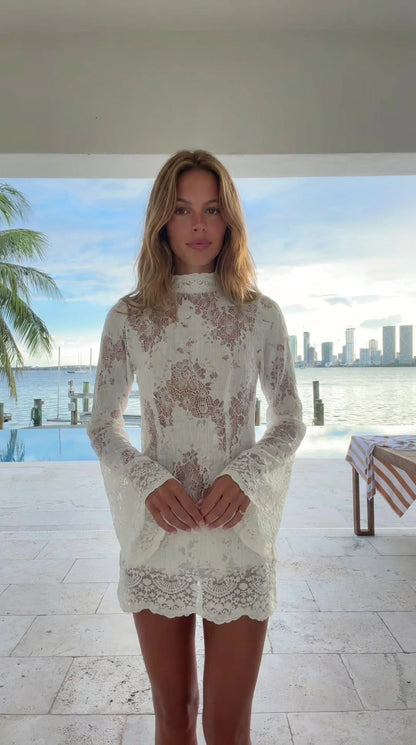 Front view of woman wearing white high neck lace mini dress with bell sleeves