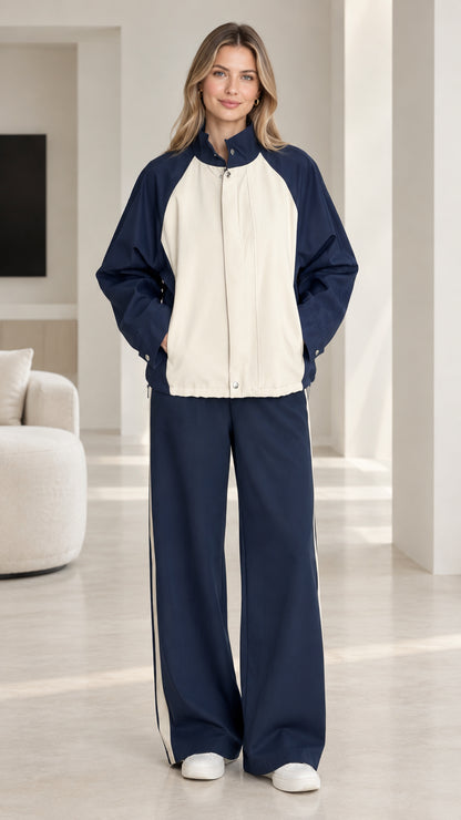 Front full-length view of woman wearing navy blue and cream colorblock tracksuit set