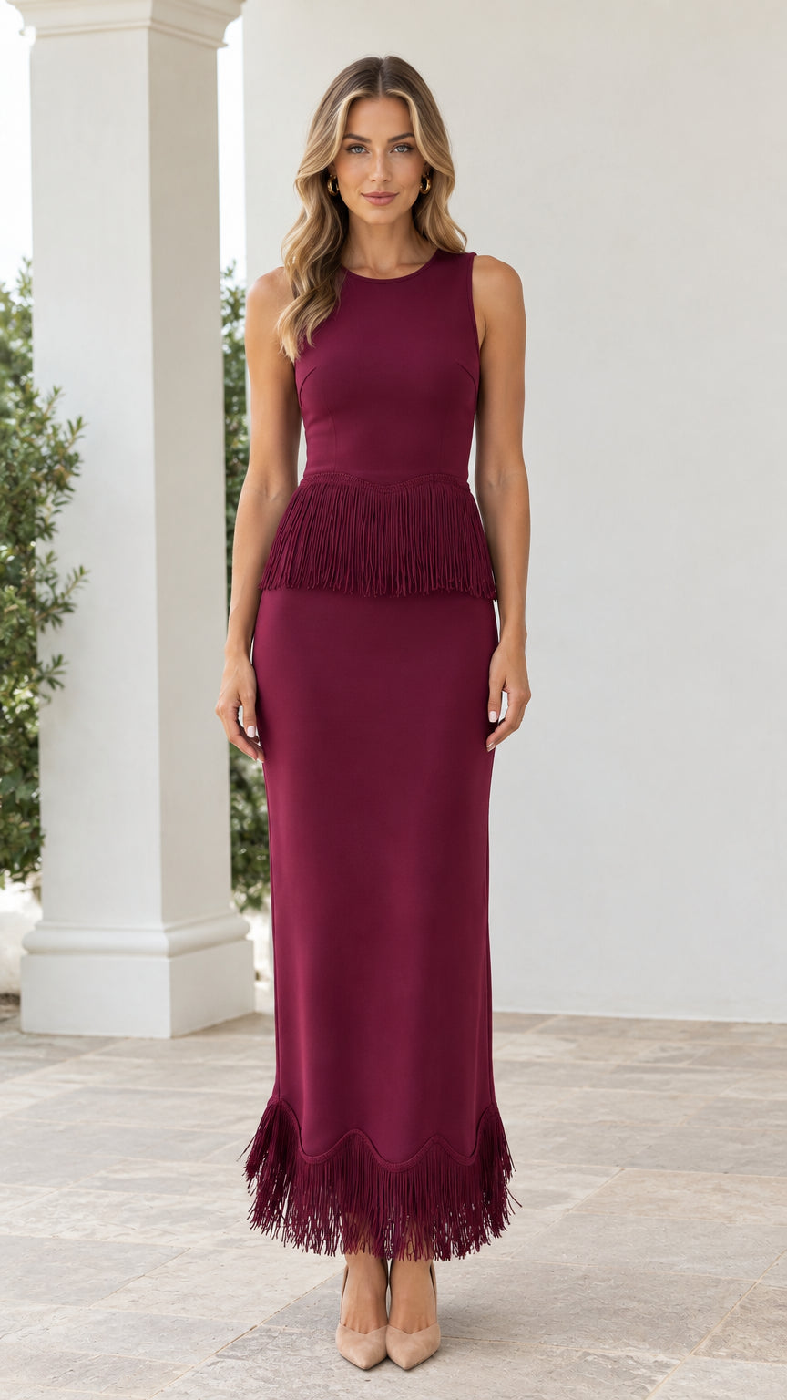 Front view of woman wearing burgundy sleeveless maxi dress with waist and hem fringe