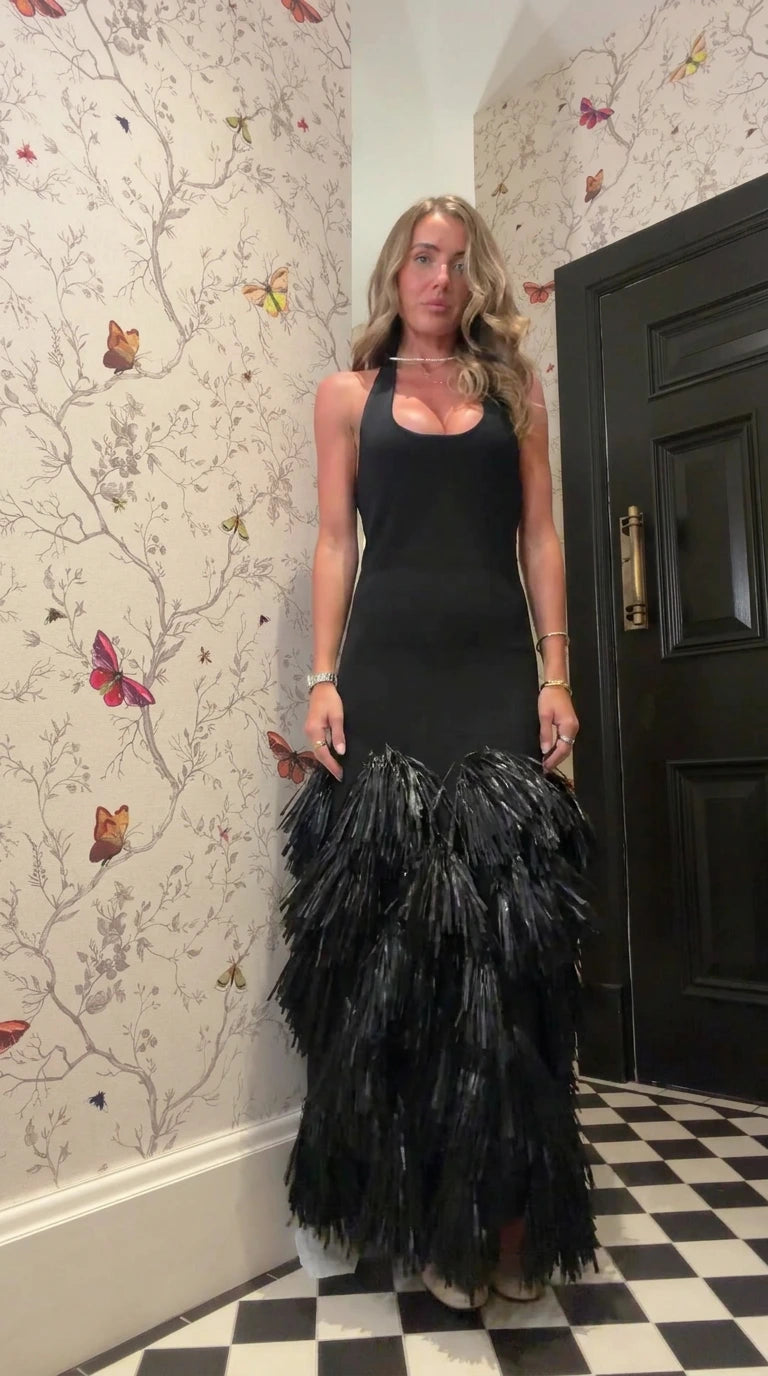 Front view of woman wearing black halter neck maxi dress with tiered fringe skirt