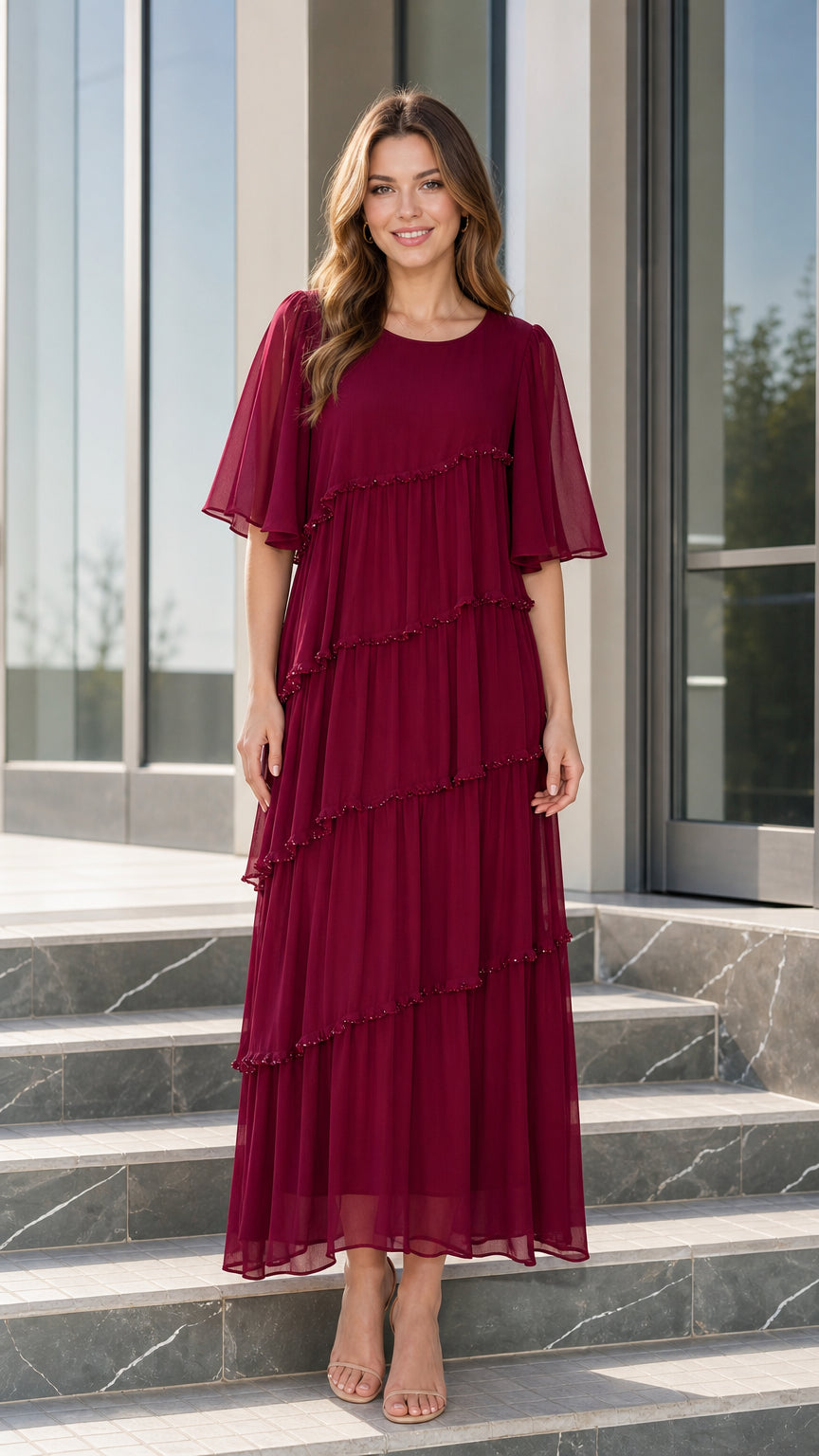 Front view of woman wearing burgundy tiered chiffon maxi dress with flutter sleeves