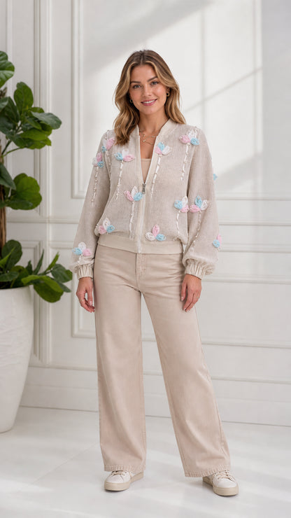 Front full-length view of model wearing beige floral appliqué zip bomber cardigan with wide-leg pants