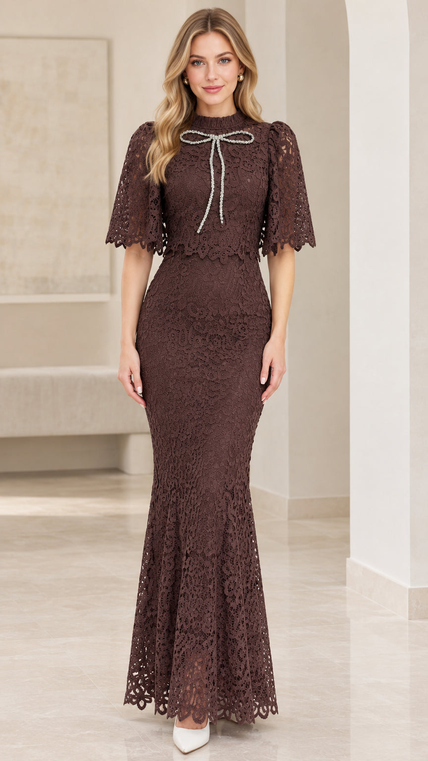 Front view of woman wearing chocolate brown lace capelet mermaid maxi dress with crystal bow
