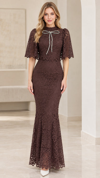 Front view of woman wearing chocolate brown lace capelet mermaid maxi dress with crystal bow