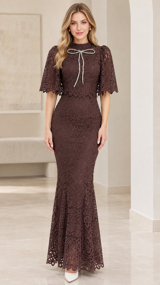 Front view of woman wearing chocolate brown lace capelet mermaid maxi dress with crystal bow