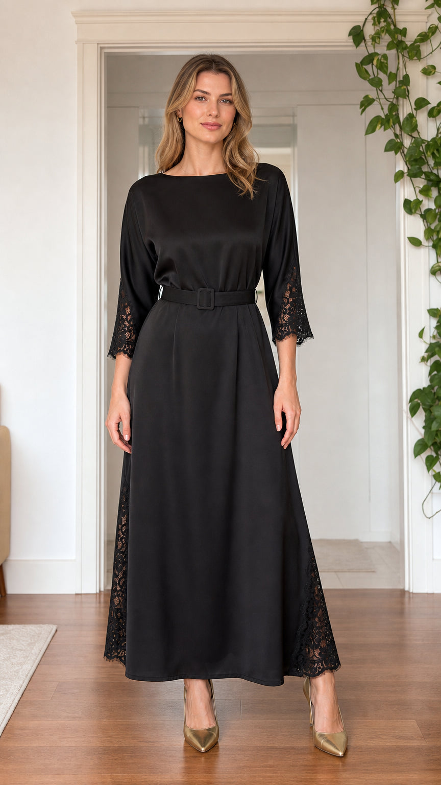 Front view of model wearing black satin boatneck maxi dress with lace trim and belt