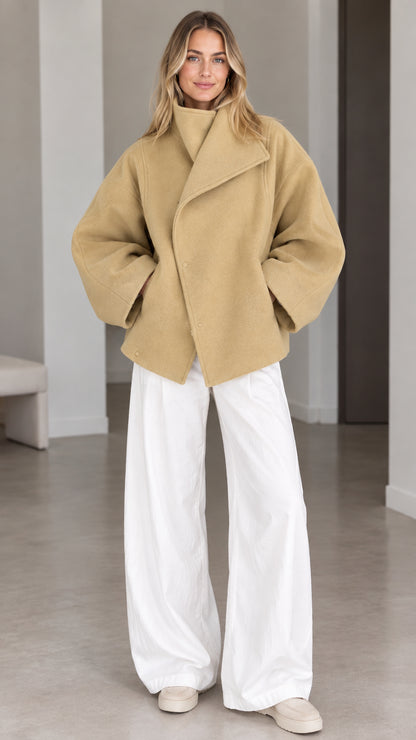Model wearing camel oversized asymmetrical high collar short coat with white wide-leg trousers