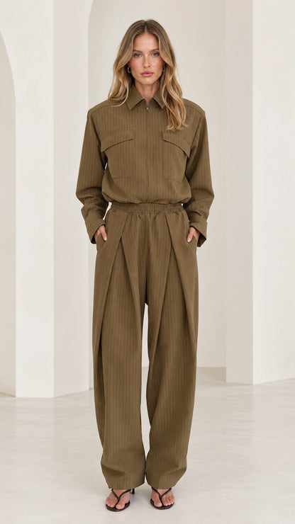 Front full-length view of woman wearing olive green long sleeve pleated wide-leg utility jumpsuit
