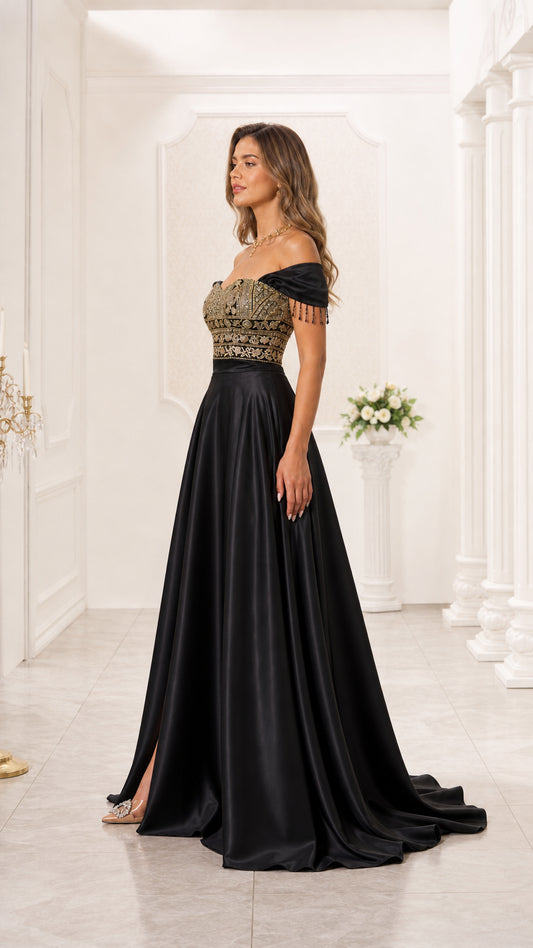 Side angle of model in black off-the-shoulder embroidered evening gown with side leg slit