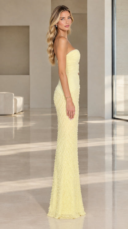 Side view of model wearing pale yellow strapless cutout floor-length evening dress