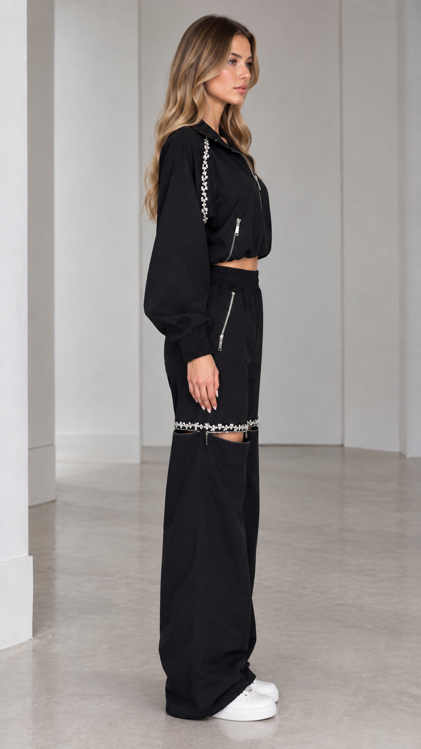 Side profile of model wearing black two-piece cropped jacket and wide-leg tracksuit set