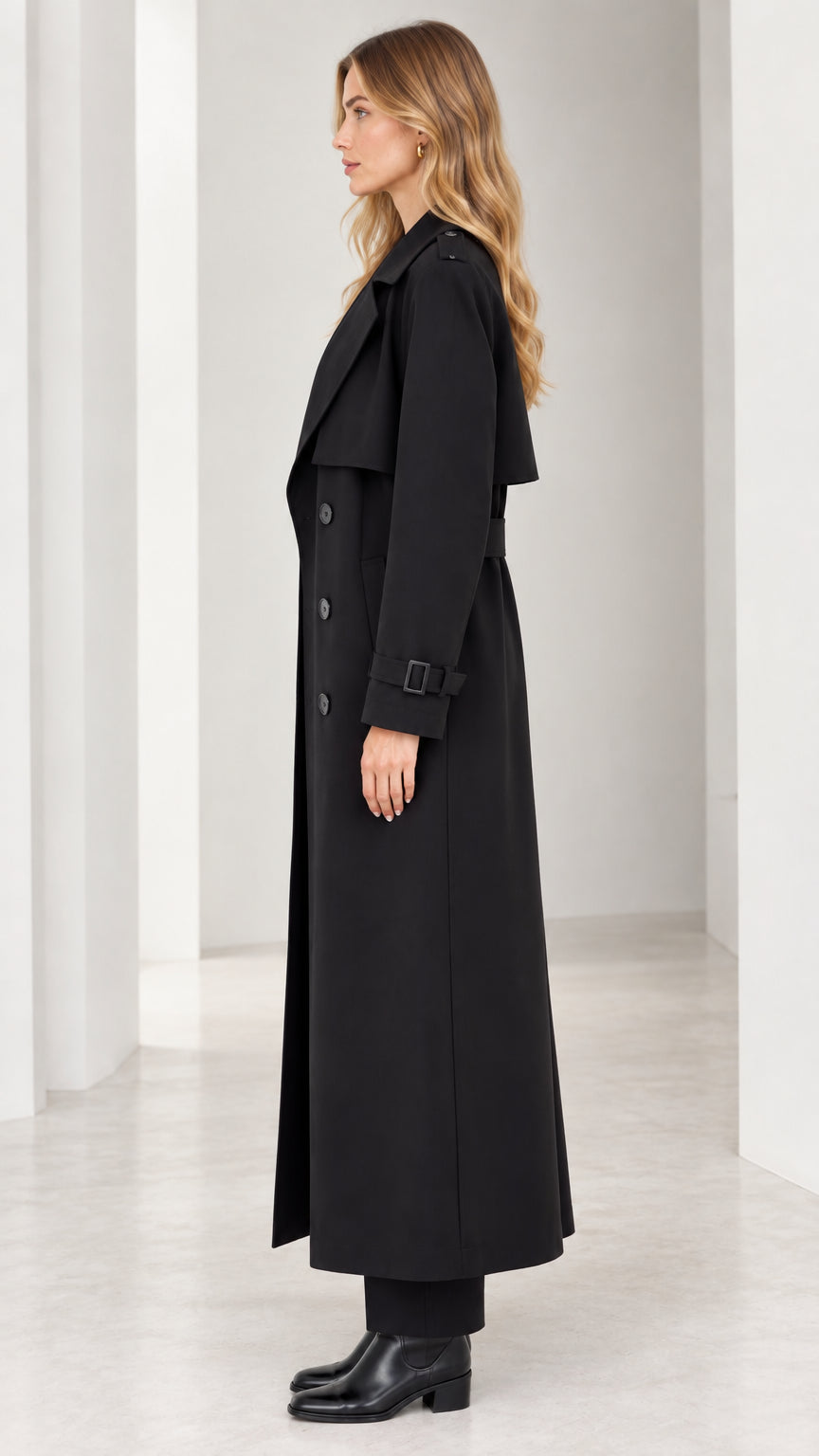 Side profile of woman wearing long black double-breasted trench coat