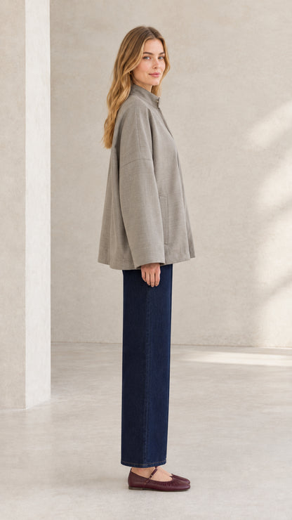 Side profile of woman modeling taupe stand collar jacket with clean swing silhouette