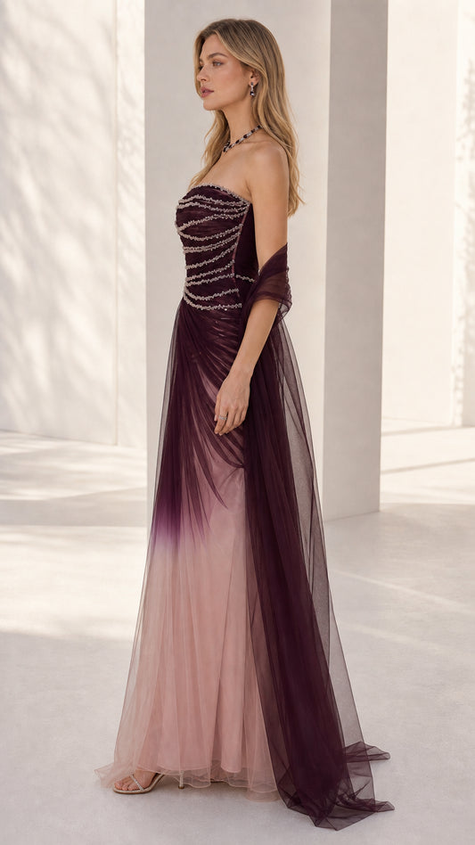 Side profile of the burgundy ombre strapless tulle gown showing fitted beaded bodice and skirt drape