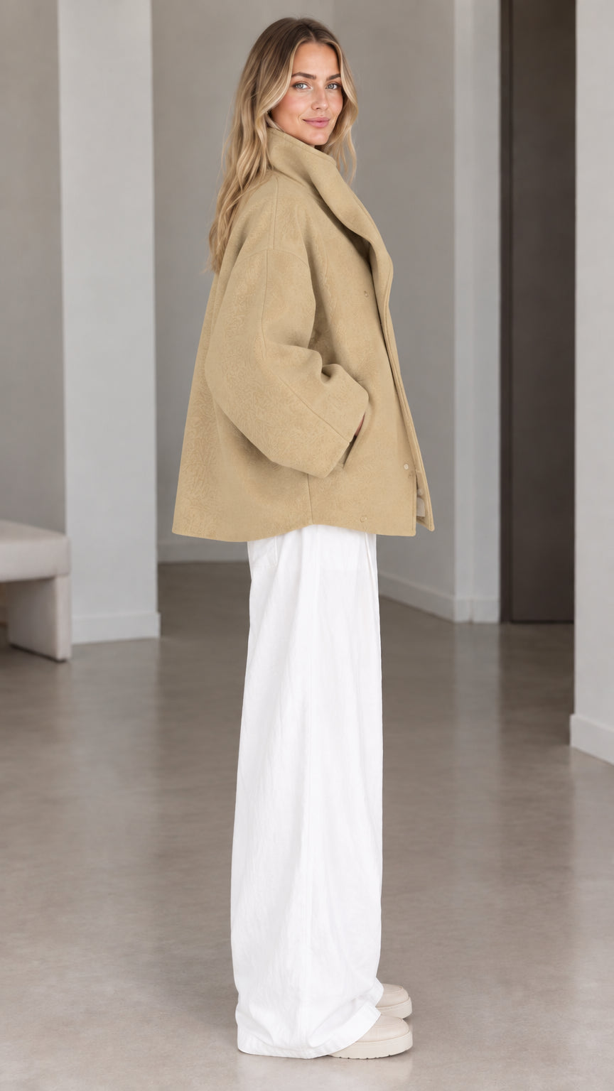 Side view of woman wearing camel wool-look short coat with dramatic collar