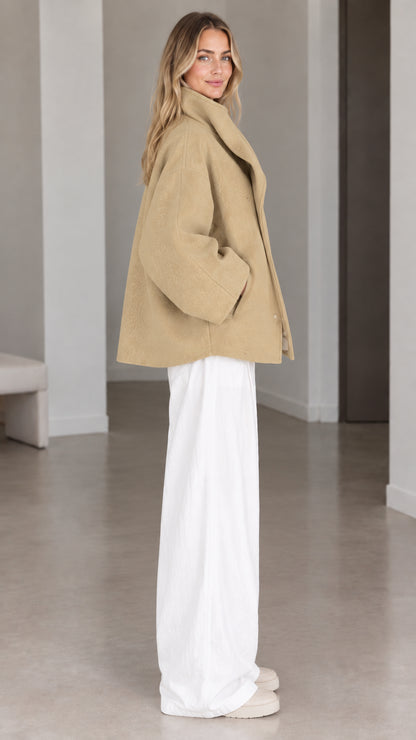 Side view of woman wearing camel wool-look short coat with dramatic collar