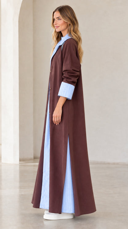 Side profile view of women's brown maxi duster coat featuring side slit and contrast hem detail