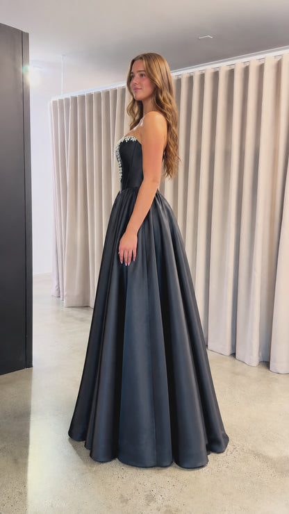 Side profile view of black strapless satin ballgown