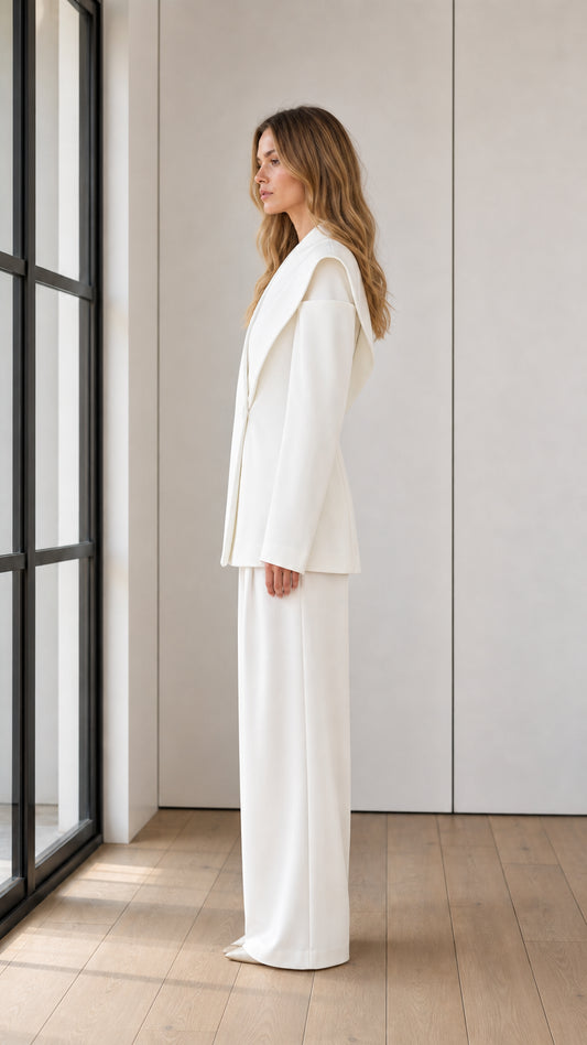 Side profile view of model wearing tailored white two-piece blazer and wide-leg suit set