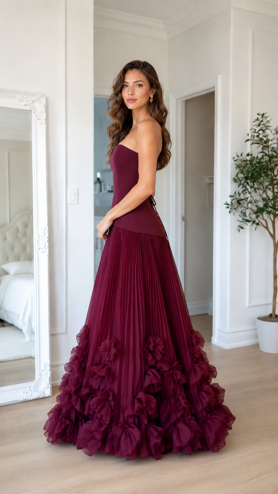 Side view of burgundy strapless formal gown with fitted bodice and pleated full skirt