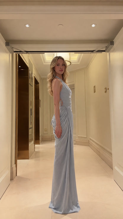 Side profile view of model wearing light blue draped halter evening gown