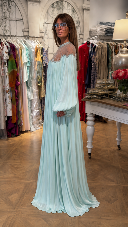 Side view of ice blue floor-length pleated dress with embellished neckline and flowing drape