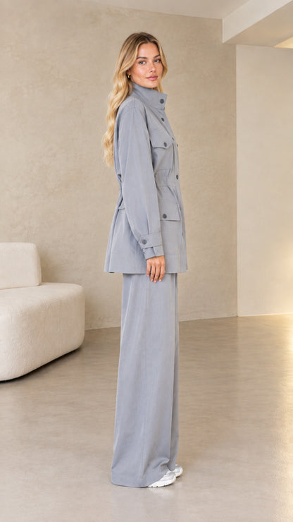 Side profile view of model in dusty blue two-piece utility suit
