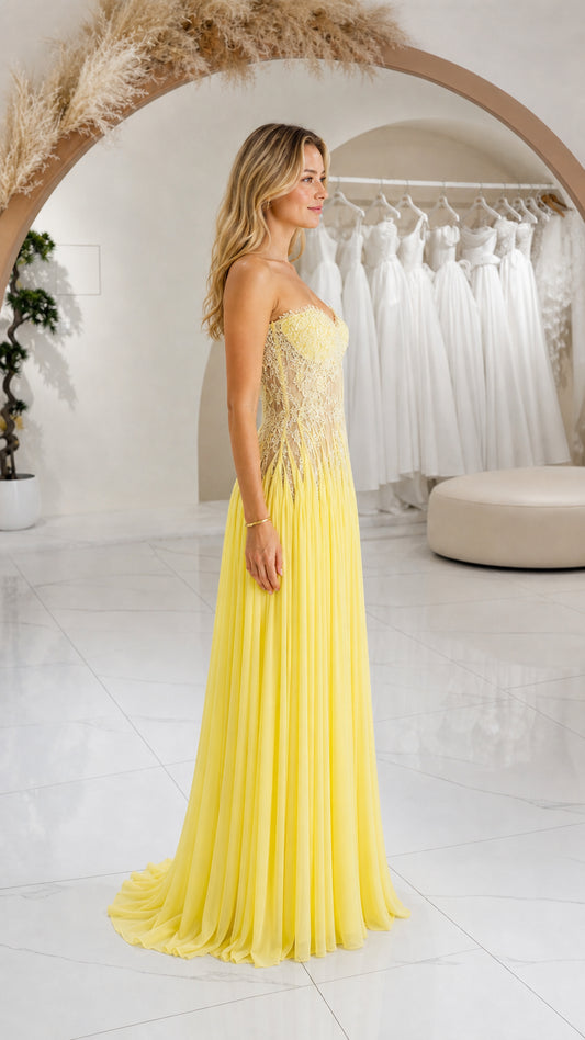 Side profile view of yellow strapless pleated chiffon maxi formal dress
