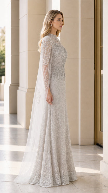 Side profile of silver beaded cape formal dress showing floor-length drape