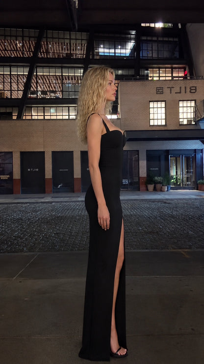 Side profile view of black corset maxi dress showing high thigh slit
