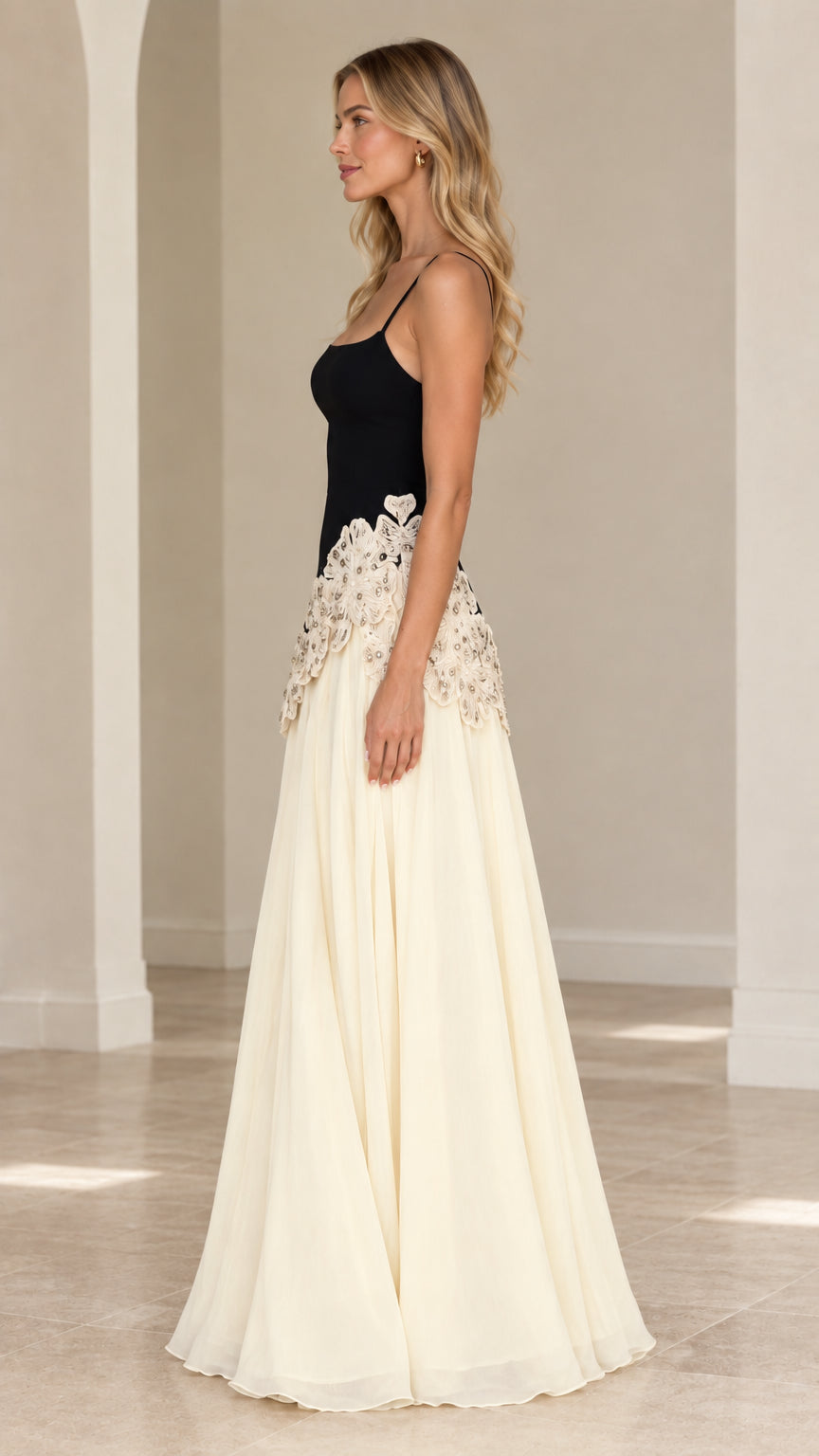 Side 3/4 view of black and cream maxi dress showing waistline embroidery and flowing skirt