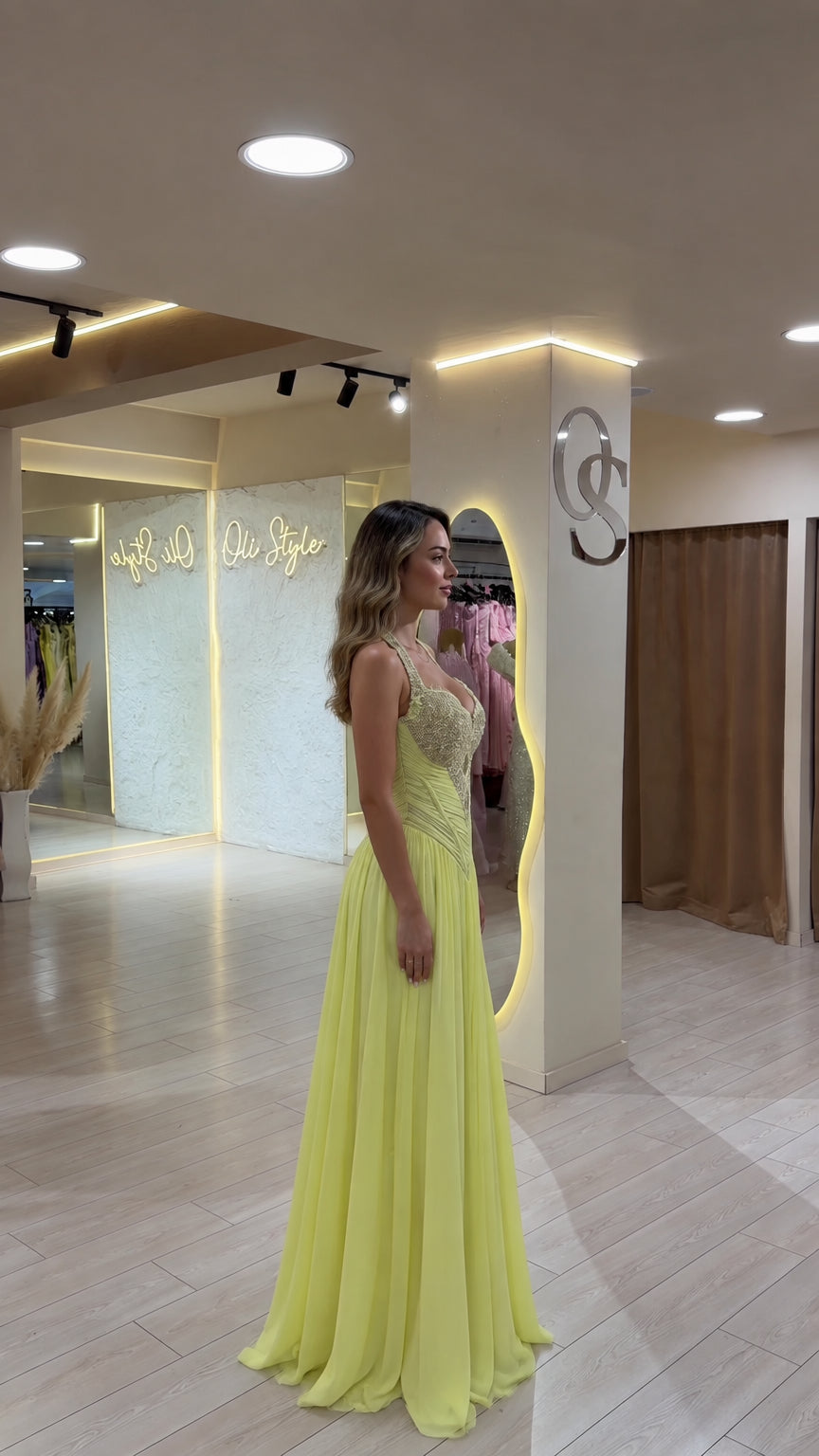 Side angle of model in pastel yellow beaded halter formal maxi dress