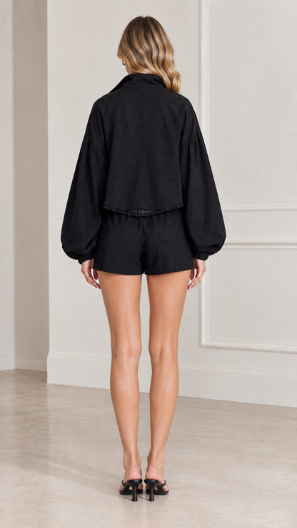 Back view of women's black balloon sleeve jacket and shorts co-ord set