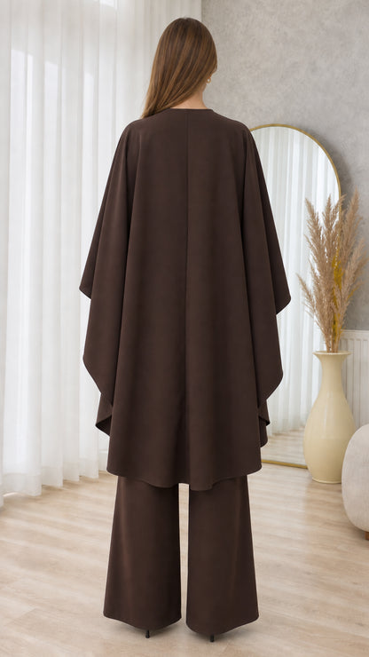 Back view of chocolate brown two-piece set highlighting high-low cape overlay and wide-leg trousers