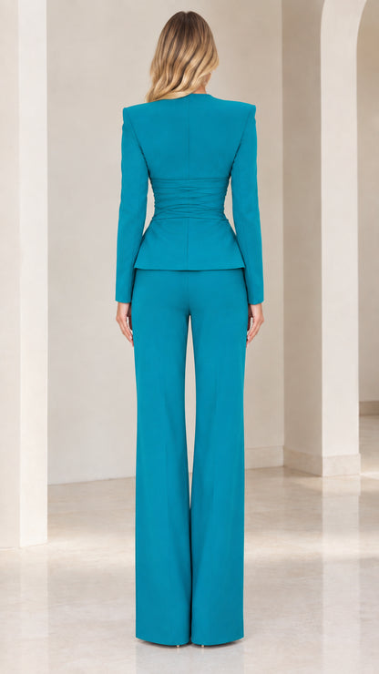 Back view of woman wearing teal long-sleeve blazer and wide-leg dress pants