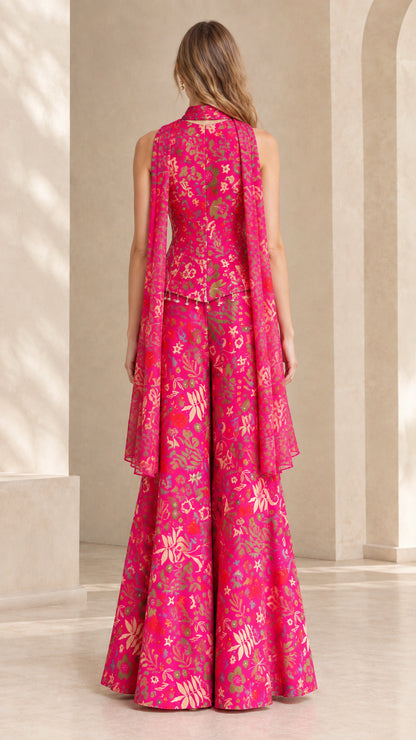Back view of model wearing fuchsia floral jumpsuit showing flowing back cape drape