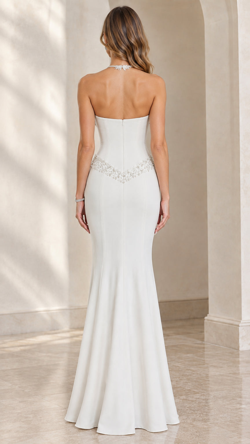 Back view of model in white open back halter beaded evening gown
