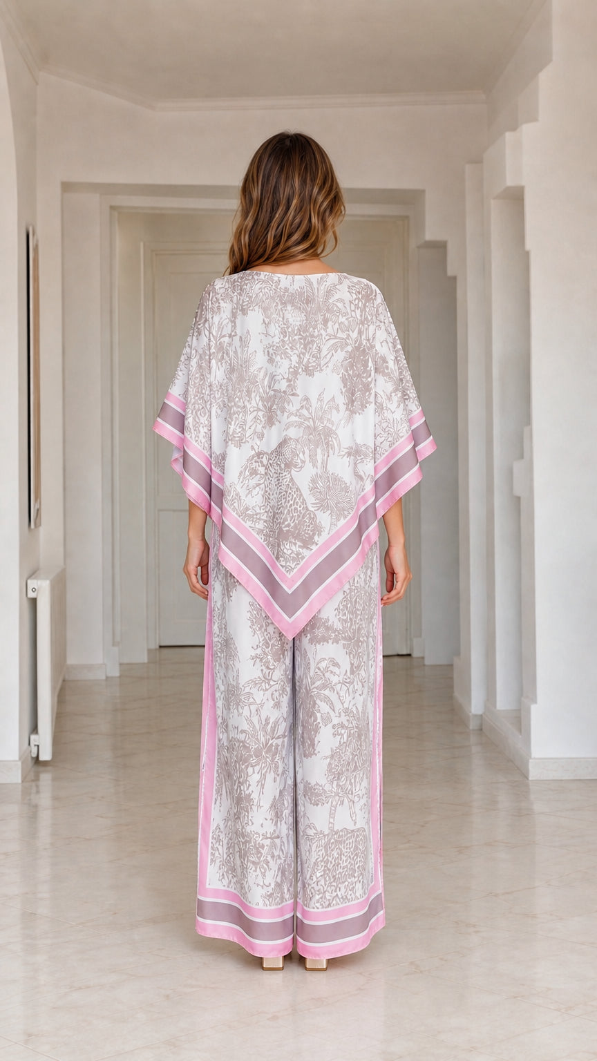 Back view of model wearing flowy white and pink poncho top and matching pants