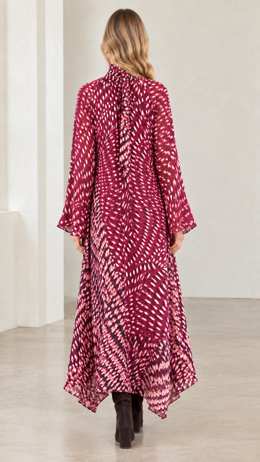 Back view of model in magenta abstract print long sleeve handkerchief maxi dress