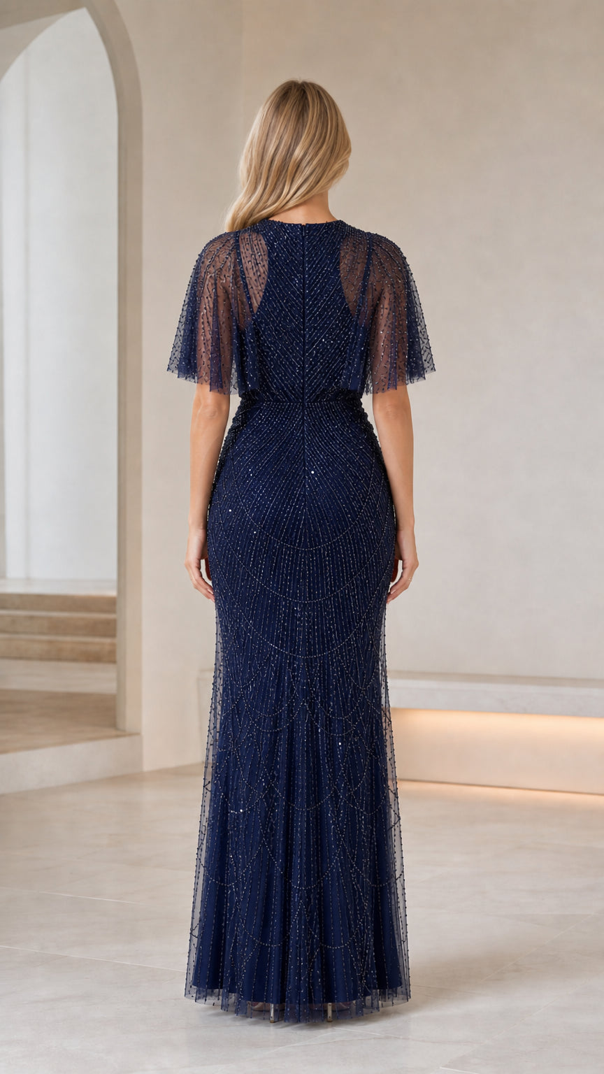 Back view of model in Navy Blue flutter sleeve beaded evening gown