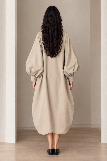 Back view of beige oversized cocoon long coat with curved hem