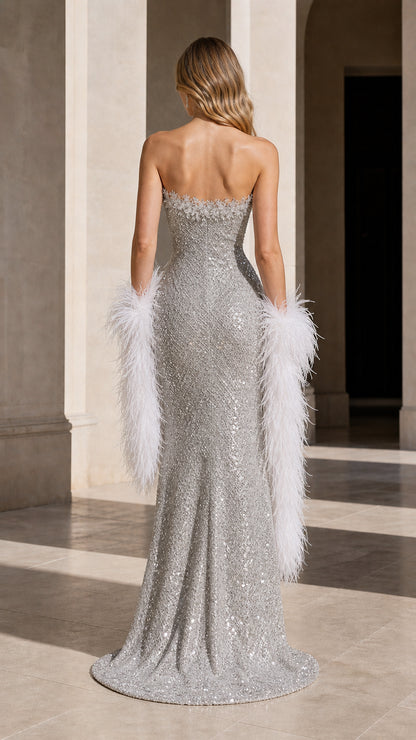 Back view of model showcasing full-length silver sequin gown with slight train