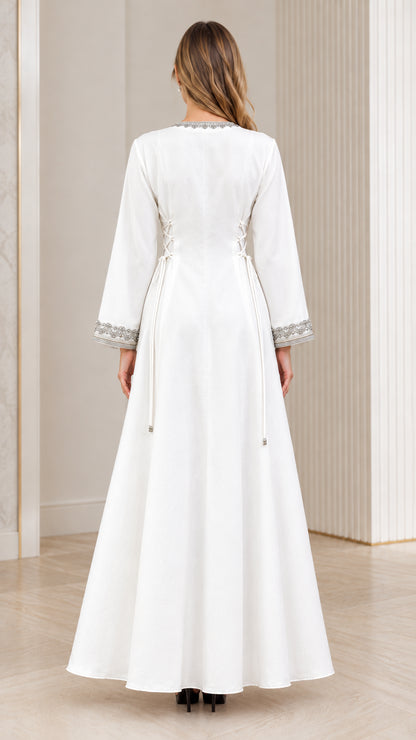 Back view of woman in elegant white long-sleeve maxi dress with waist ties