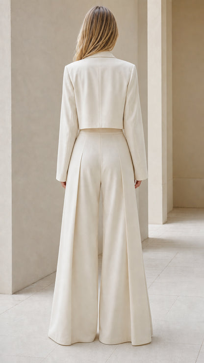 Back view of woman in cream cropped jacket and high-waisted flowing trousers